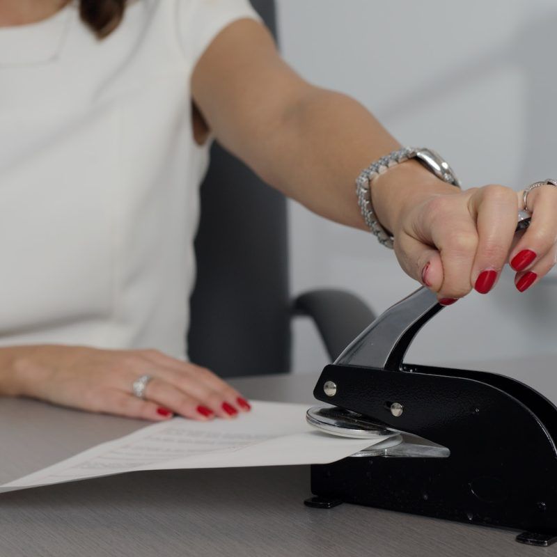 woman in white shirt holding pen writing on white paper
