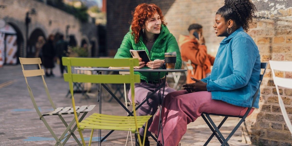 a couple of women sitting at a table outside